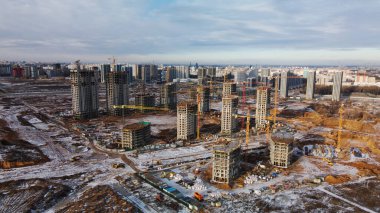 Construction site. Construction of modern high-rise buildings. Work construction cranes. Snow covered earth. Aerial photography.