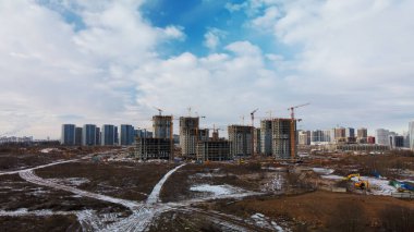 Construction site. Construction of modern high-rise buildings. Work construction cranes. Snow covered earth. Aerial photography.