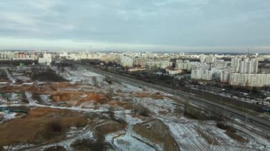 Construction site in a city vacant lot. Close to populated urban areas. Traces of heavy construction equipment are visible on the ground. Snow covered earth. Aerial photography.