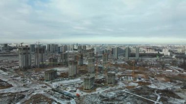 Construction site. Construction of modern high-rise buildings. Work construction cranes. Snow covered earth. Aerial photography.
