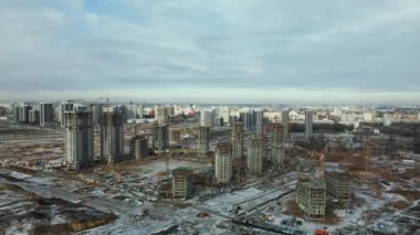 Construction site. Construction of modern high-rise buildings. Work construction cranes. Snow covered earth. Aerial photography.