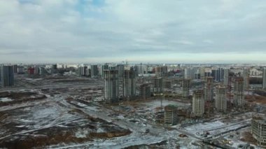Construction site. Construction of modern high-rise buildings. Work construction cranes. Snow covered earth. Aerial photography.