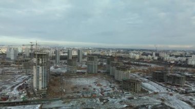Construction site. Construction of modern high-rise buildings. Work construction cranes. Snow covered earth. Aerial photography.