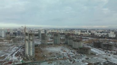 Construction site. Construction of modern high-rise buildings. Work construction cranes. Snow covered earth. Aerial photography.