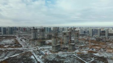 Construction site. Construction of modern high-rise buildings. Work construction cranes. Snow covered earth. Aerial photography.