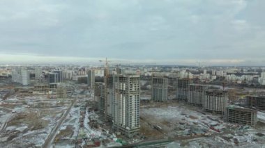 Construction site. Construction of modern high-rise buildings. Work construction cranes. Snow covered earth. Aerial photography.