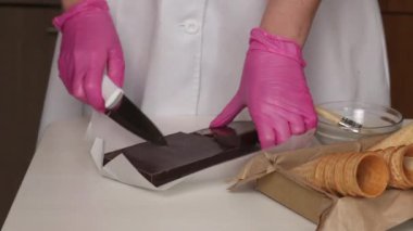 Bir kadın çikolatayı çatlatıyor. Yakınlarda waffle külahları var. Çikolata ve marşmelovla boynuz yapar.