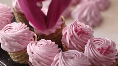 Şekerlemeli waffle külahları. Karton raflarda. Bir kadın şekerlemeleri dekoratif şekerlerle süslüyor. Yakın plan.