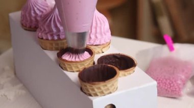 Bir kadın waffle külahında marşmelov yapıyor. Pasta torbasıyla. İçinden çikolata bulaşmış waffle külahları. Yakın plan..