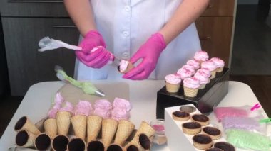 Bir kadın waffle külahında marşmelov yapıyor. Dekoratif malzemeli. İçinden çikolata bulaşmış boynuzlar..