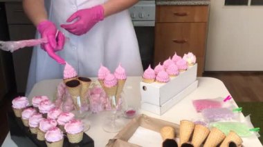 Bir kadın kremalı waffle külahı yapıyor. Süslemeler ve mastik kar taneleriyle süslenmiş. Ortam planı.