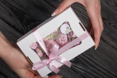 Bir kadın elinde bir kutu marşmelov tutuyor. Hediye kutusunda ev yapımı marşmelov. Fiyonka bağlanmış bir kurdeleyle.