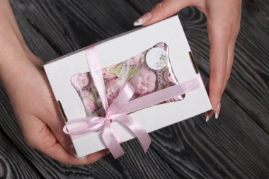 Bir kadın elinde bir kutu marşmelov tutuyor. Hediye kutusunda ev yapımı marşmelov. Fiyonka bağlanmış bir kurdeleyle.