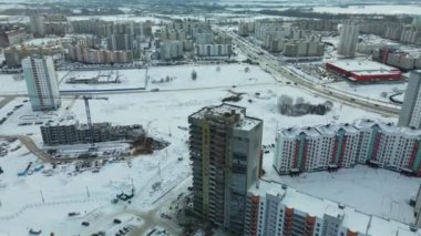 Modern bir şehir bloğunun inşaat alanı. Yüksek binalar yapım aşamasında. İnşaat kulesi vinçleri. Kışın inşaat alanında. Gün batımında hava fotoğrafçılığı.