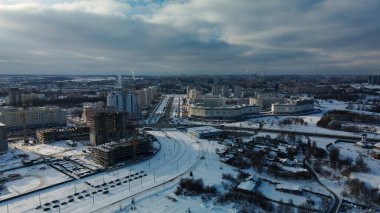 Modern bir şehir bloğunun inşaat alanı. Yüksek binalar yapım aşamasında. İnşaat kulesi vinçleri. Kışın inşaat alanında. Gün batımında hava fotoğrafçılığı.