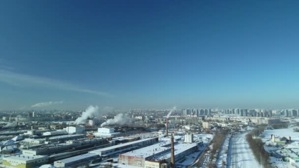 被雪覆盖的工厂建筑 工厂烟雾烟囱 附近有一条铁路 你可以看到城市的街区 冬季工业景观 空中摄影 — 图库视频影像