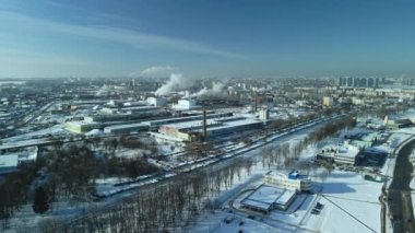 Karla kaplı fabrika binaları. Fabrika duman bacaları. Yakınlarda bir demiryolu var. Şehir bloklarını görebilirsin. Kış endüstriyel manzarası. Hava fotoğrafçılığı.