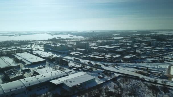 雪に覆われた工場の建物 鉄道だ 夕日のバックライトで 冬の産業風景 旋回飛行 空中写真 — ストック動画