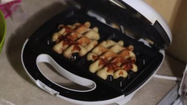 Bir kadın ısıtılmış waffle ızgarasını açar ve bitmiş waffleları çıkarır. Kahvaltı hazırlığı. Yakın plan..