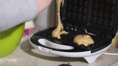 Bir kadın hamuru ısıtılmış waffle ızgarasına koyar. Kahvaltı hazırlığı. Yakın plan..