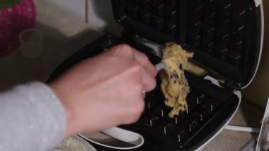 Kadın açılır, hamuru ısıtılmış waffle ızgarasına koyar ve kapatır. Kahvaltı hazırlığı. Yakın plan..