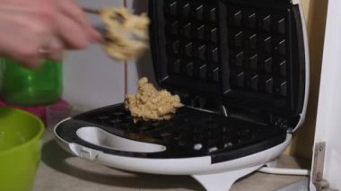 Bir kadın waffle ızgarasına hamur koyar. Kahvaltı hazırlığı. Yakın plan..