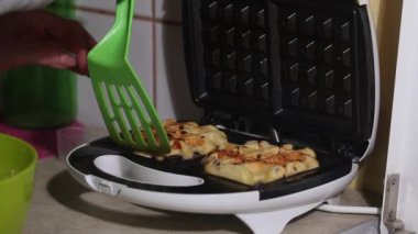 Bir kadın waffle ızgarasından taze yapılmış waffle yapar. Kahvaltı hazırlığı. Yakın plan..