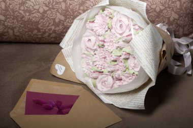 Bir buket marşmelov. Zephyr çiçekleri. El işi kağıdına sarılmış. Yanında bir tebrik kartı ve bir zarf var. Yakın plan..