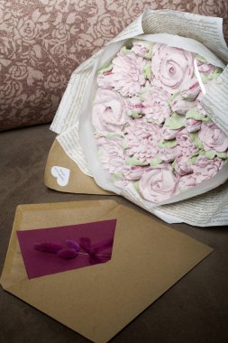 Bir buket marşmelov. Zephyr çiçekleri. El işi kağıdına sarılmış. Yanında bir tebrik kartı ve bir zarf var. Yakın plan..