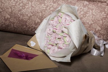 Bir buket marşmelov. Zephyr çiçekleri. El işi kağıdına sarılmış. Yanında bir tebrik kartı ve bir zarf var. Yakın plan..