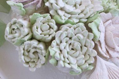 Güller, laleler ve marşmelovlardan kasımpatılar. Zephyr çiçekleri. Üzerine pudra şekeri serpilmiş..