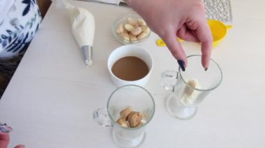 Bir kadın bardakta tatlı yapar. Savoiardi kurabiyesi ve kremalı tatlı. Tiramisu kurabiyeleri