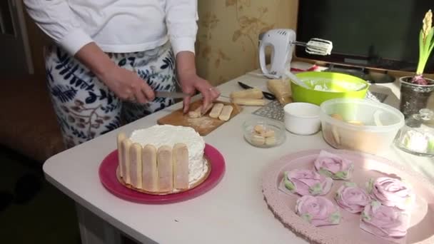 女性はサヴォアールディのクッキーでケーキをカバーしています サヴォイアルディのクッキーとマシュマロのバラのケーキ — ストック動画