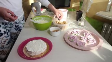 Bir kadın kurabiye kekini istifliyor. İçinde Savoiardi kurabiyeleri ve marshmallow gülleri olan kek.