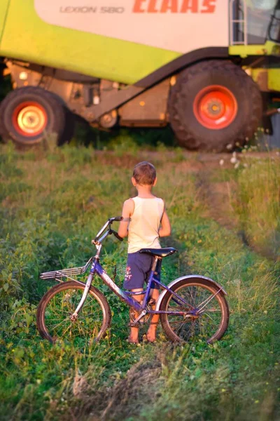 Small rural children always love large agricultural machinery, children are delighted with combines, tractors and other equipment. The title of this photo is \