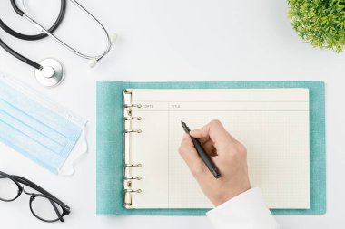 Masada çalışan tıp çalışanı defter üst görünümüne yazar