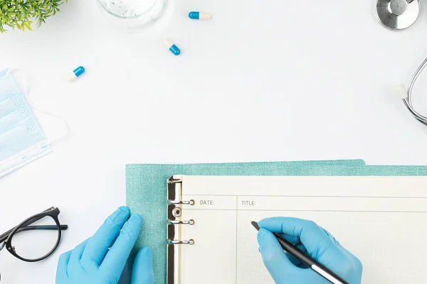 Trabajador médico en la mesa escribir en cuaderno vista superior Imagen de stock