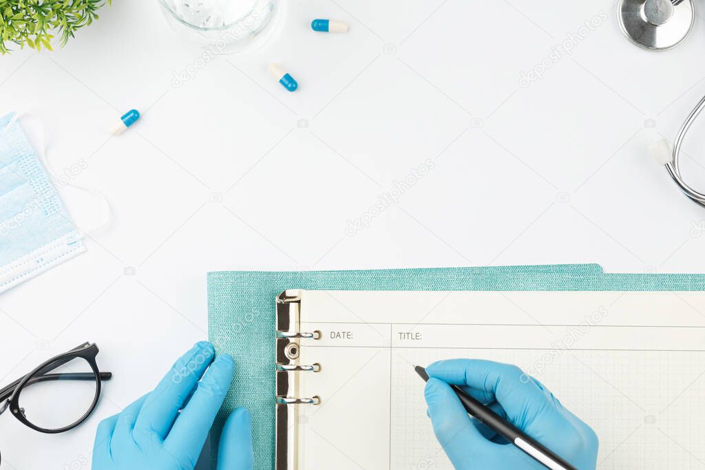 Medical worker at table write in notebook top view
