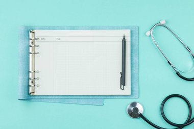 Yeşil arkaplanda not defteri olan stetoskop.