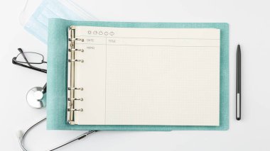 Kalem ve gözlüklü tıbbi günlük beyaz izole arkaplan manzaralı. Doktor masa konsepti. Stetoskop ve sargı bezi düz yerde yatan hastane iş yeri konsepti.