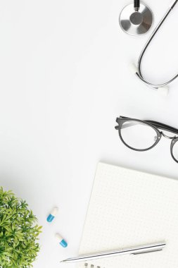 Kalem ve gözlüklü düz dizüstü bilgisayarı aç. Tıbbi maskeli steteskop ve izole edilmiş beyaz arka plan görüşlü haplar. Doktorlar masaüstü konsepti.