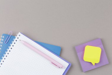 Üzerinde leylak kalem ve gri arka planda çıkartmalar olan spiral bir defter aç. Çalışma masası. Üst Manzara. Okul konseptine geri dönelim. Düz yatıyordu.