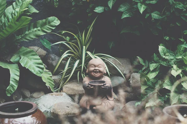 E Patung simbol batu coklat Buddha memegang mangkuk tersenyum. Salin alam tropis meninggalkan kebun tanaman. Misterius tenang jiwa meditasi suasana hati Buddha budaya. Hijau pucat, lebih banyak nada dalam stok — Stok Foto