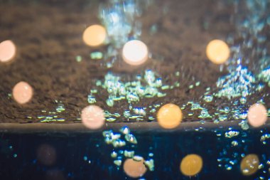 Camdan geçen gerçek hava kabarcığı. Görüntü turuncu ışık fenerlerinin etrafında parlıyor. Seçici odaklanma. Akşam yaşam tarzı, tatil havası, alt deney, arka plan zenginlik tasarımı