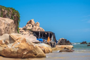 Gerçek doğa güzelliği arka planı. Deniz okyanusu dev kayalar sahil kıyısı manzarası güneş günü mavi gökyüzü, soluk kahverengi turuncu kayalar. Sailor barakasında basit yaşam tarzı balıkçılık malzemeleri var. Tatil gezisi