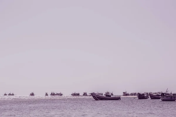 Lichtroze paarse grijze toon zeegezicht heldere hemel uitzicht. Echte natuur schoonheid achtergrond. motorboten varen aangemeerd ondiep water rand zand strand baai rustige rimpel zee. Visserijstijl. reis vrijetijdsbesteding — Stockfoto