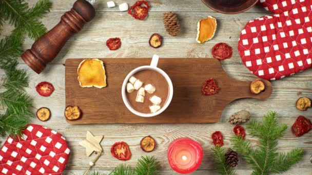 Mano è cospargere di cioccolata calda con marshmallow e cannella. Intorno a su un tavolo di legno sono accessori festivi. Concetto di umore di Natale e Anno nuovo — Video Stock