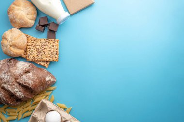Mavi arka plan manzaralı taze yiyecekler. Ekmek, çikolata, süt, yumurta ve diğer ürünler. Boşluğu kopyala.