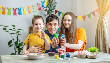 Paskalya yumurtalarını dekore edilmiş bir odada boyamak. Anne, baba ve çocuk eğleniyor ve tatil için hazırlanıyorlar..