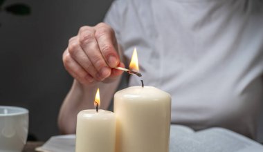 Kadın rahatlatıcı bir atmosfer, uyum ve denge yaratmak için mum yakıyor. Aromaterapi kavramı, sabah ve akşam ayinleri, meditasyonlar. Kapat..